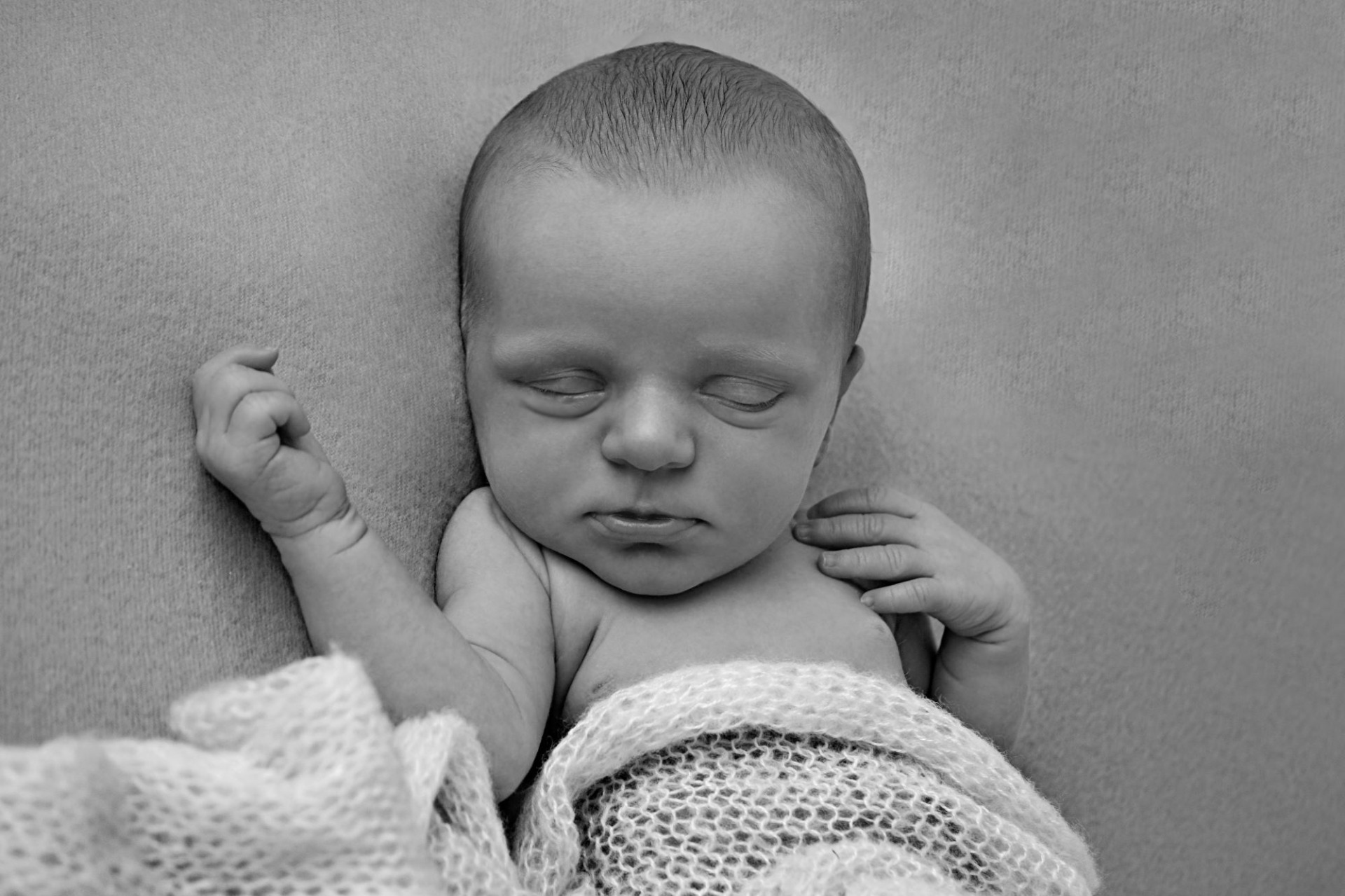 Černobílá fotografie z novorozeneckého, newborn focení. Několika denní miminko má na sobě růžovou deku a růžové pozadí. Domácí fotoateliér Mladá Boleslav.