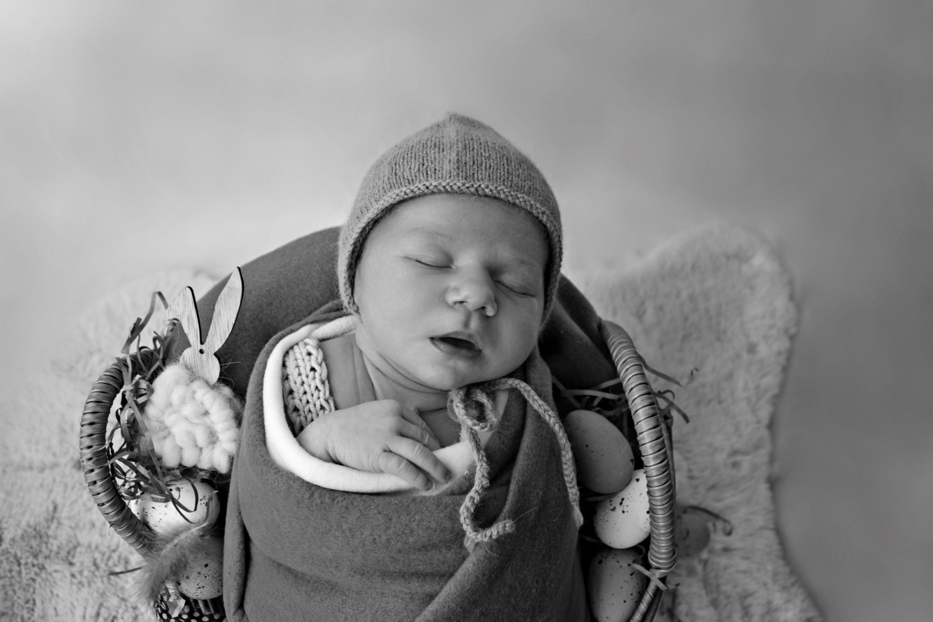 Černobílá fotografie z novorozeneckého, newborn focení. Několika denní miminko má na sobě modré oblečení a bílé pozadí. Domácí fotoateliér Mladá Boleslav.